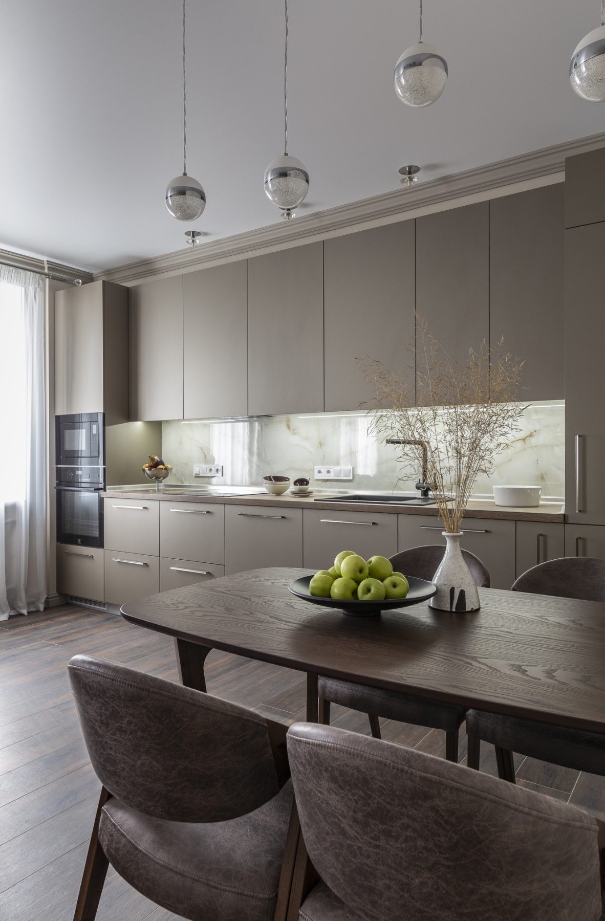 Kitchen and dining area with a dark wood table and glass pendant lights