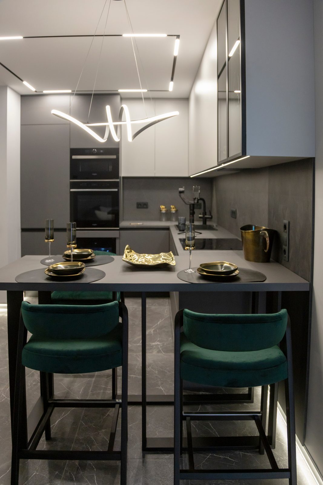 Kitchen with a breakfast bar, green velvet bar stools and a sculptural pendant light