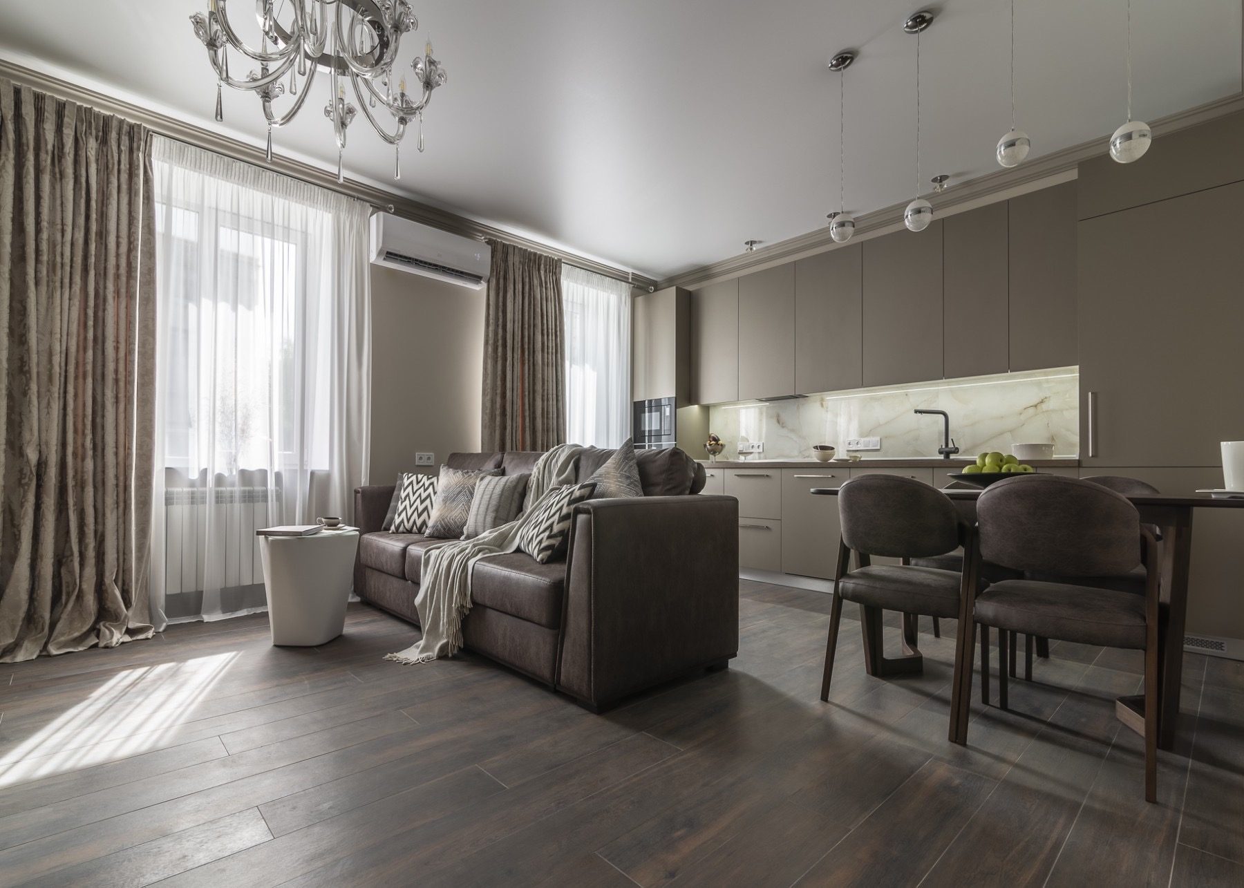 Living room with a grey sofa open to the kitchen and dining area