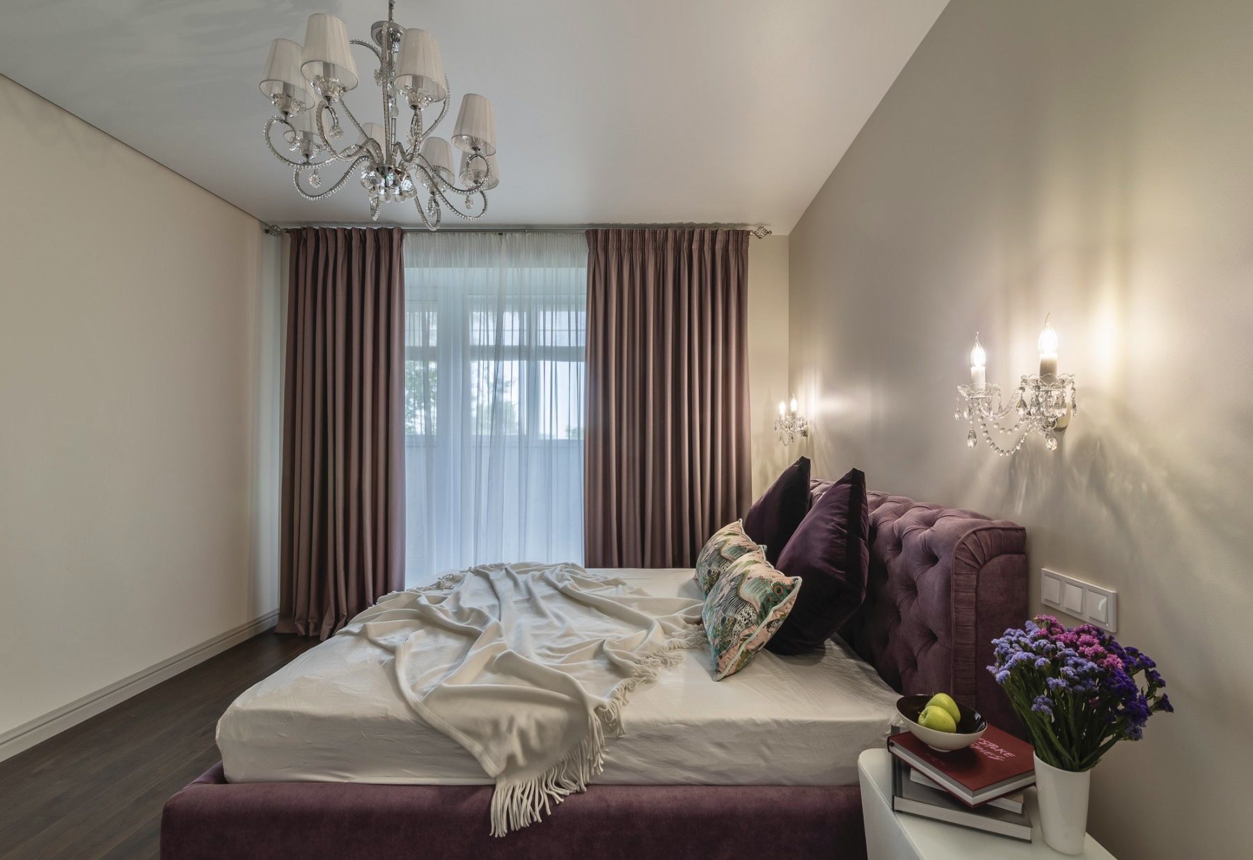Bedroom with a velvet bed, chandelier and dark curtains
